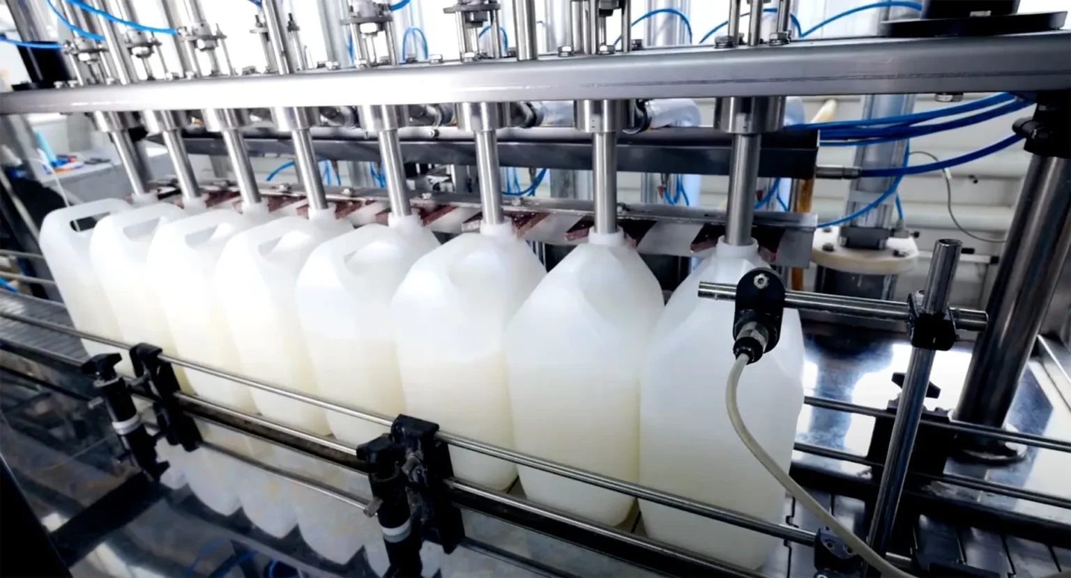 Automated filling machine dispensing liquid into plastic bottles on a production line